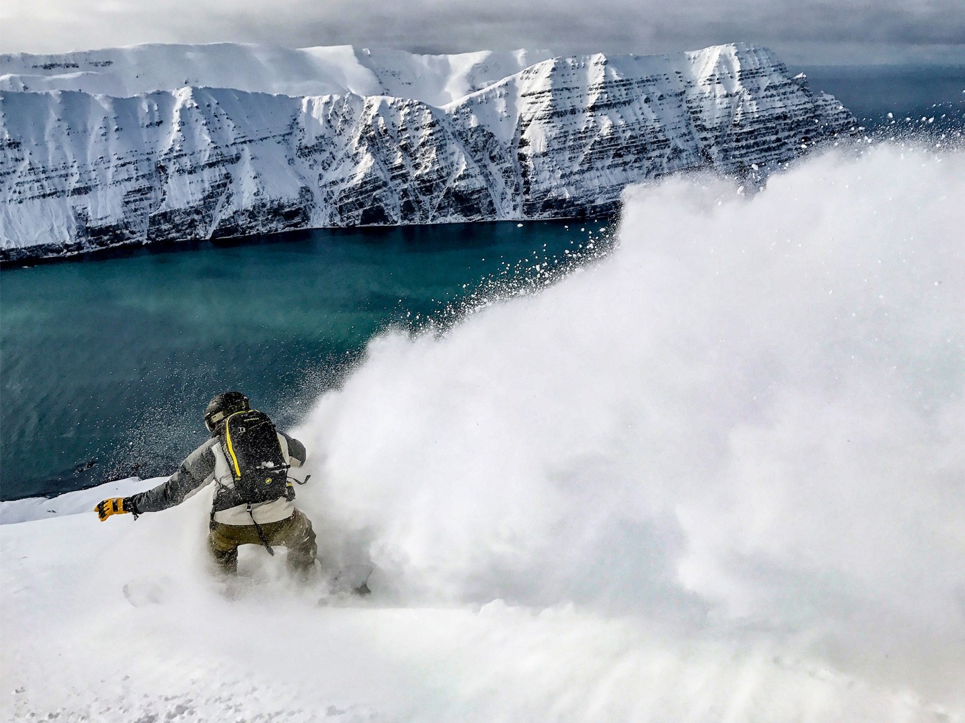 Person snowboarding, carving atop a snowy mountain.